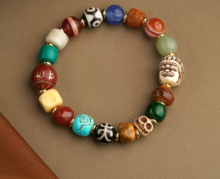 Many Wishes bracelet with multicolor patterned beads, gold-tone spacers and carved details on a warm brown surface