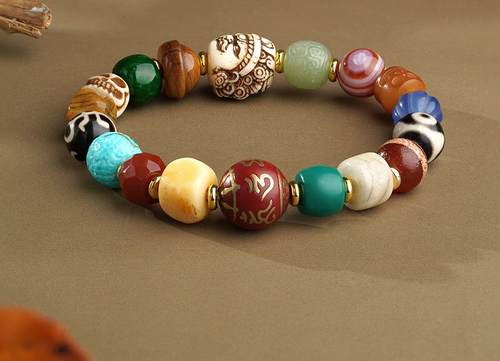 Angled view of the Many Wishes bracelet, with an inscribed red focal bead, contrasting eye patterns and sculpted details.