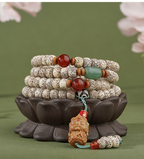 Star & Moon meditation beads arranged on a dark lotus-shaped stand, with cream speckled beads and an amber-colored sculpted pendant.