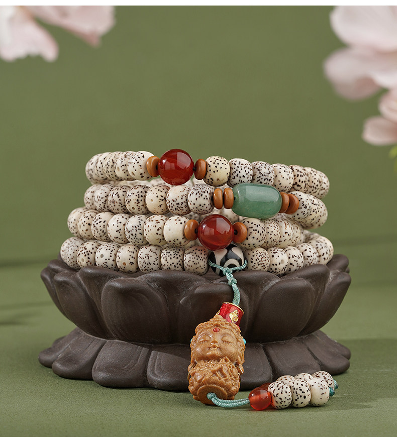 Star & Moon meditation beads arranged on a dark lotus-shaped stand, with cream speckled beads and an amber-colored sculpted pendant.