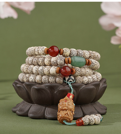 Star & Moon meditation beads arranged on a dark lotus-shaped stand, with cream speckled beads and an amber-colored sculpted pendant.